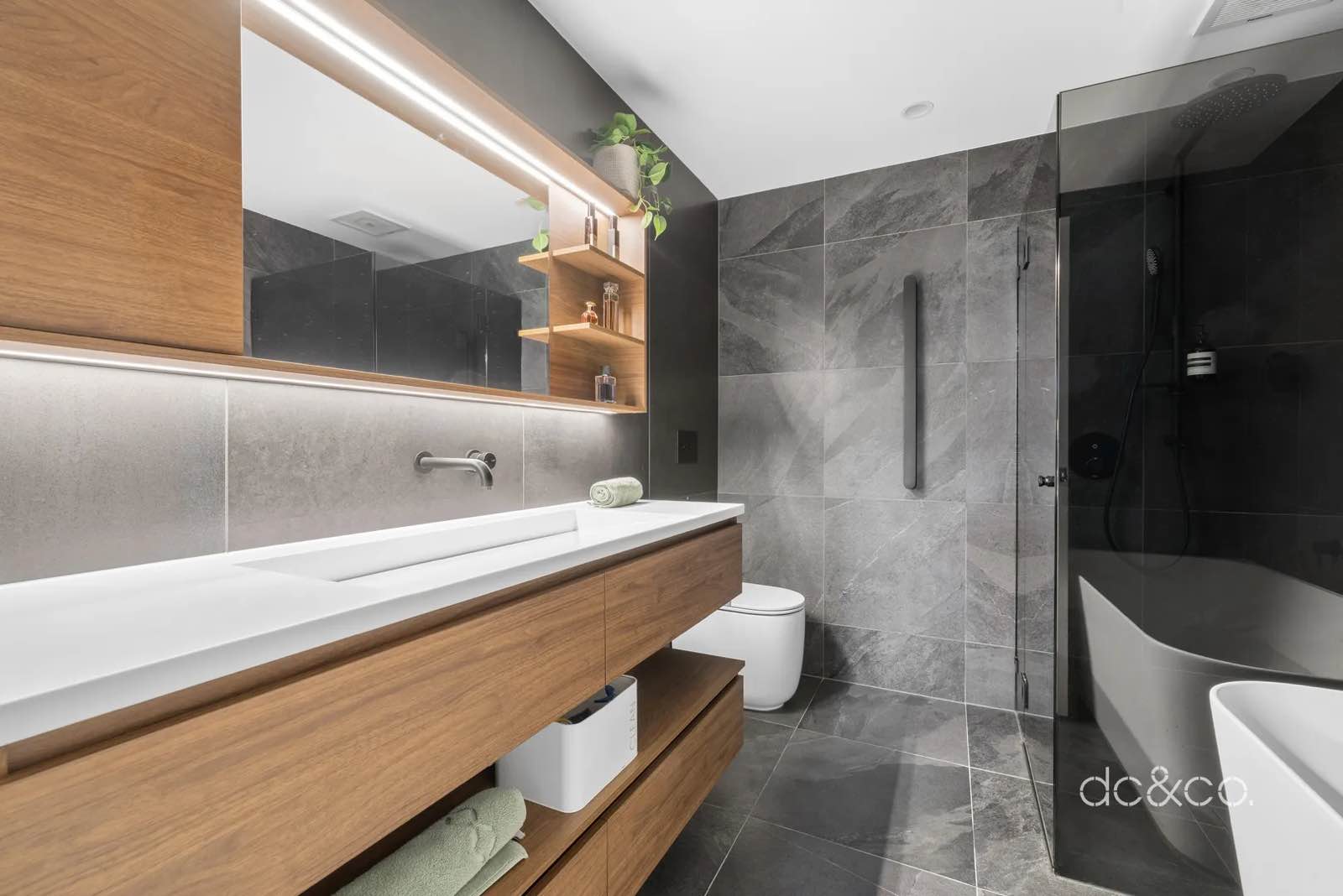 Ensuite with freestanding bath, frameless shower screen and large-format grey tile
