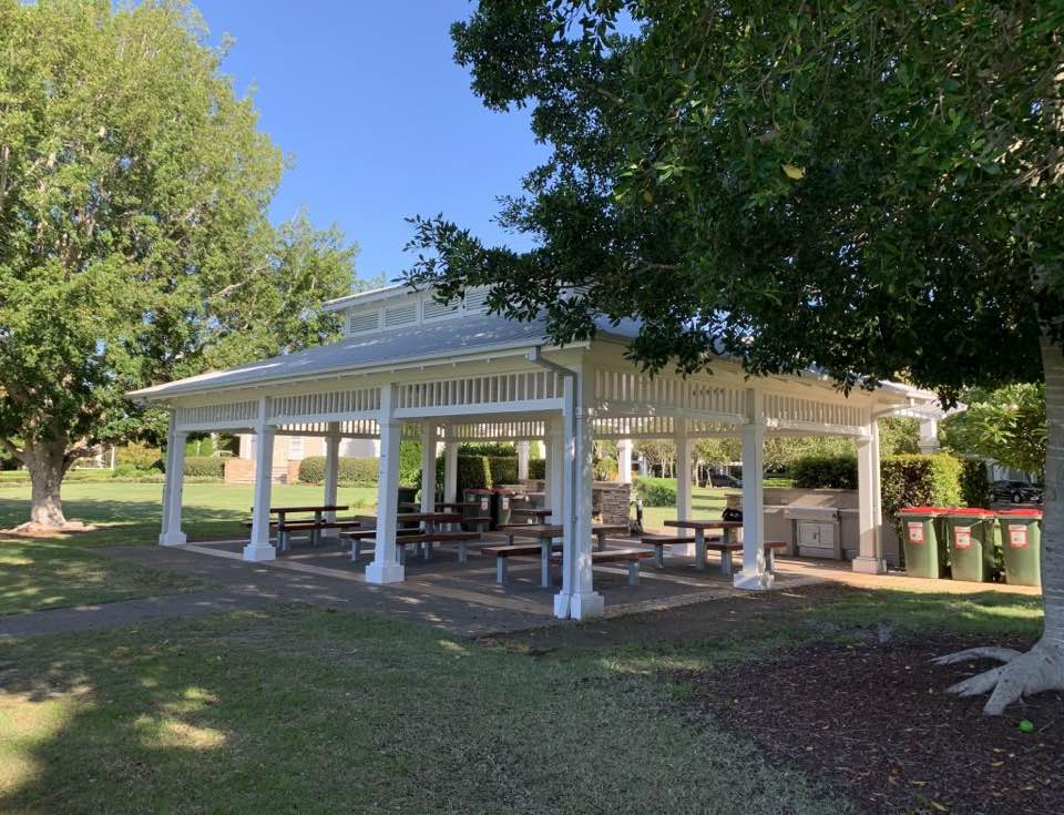 The roofed BBQ pavilion with six picnic tables and two built-in barbecues, beside the Community Hall