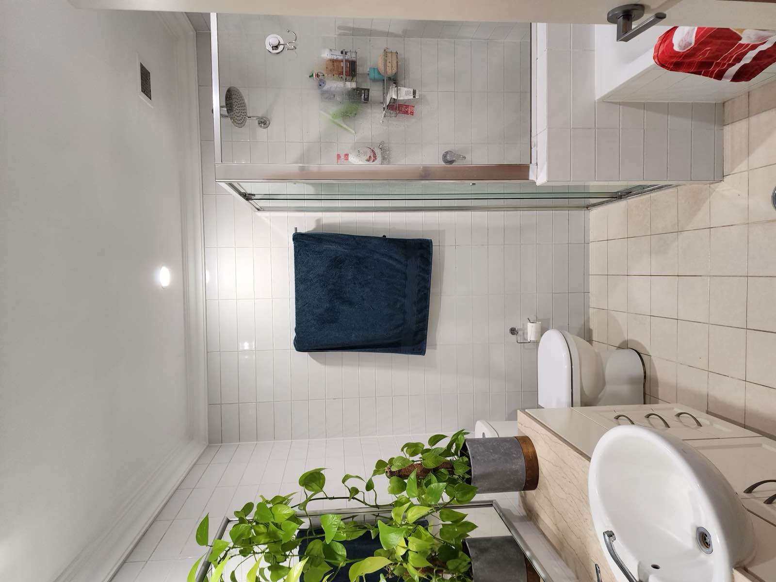 Ensuite before renovation: built-in bath with a chrome-framed shower screen and white subway tile