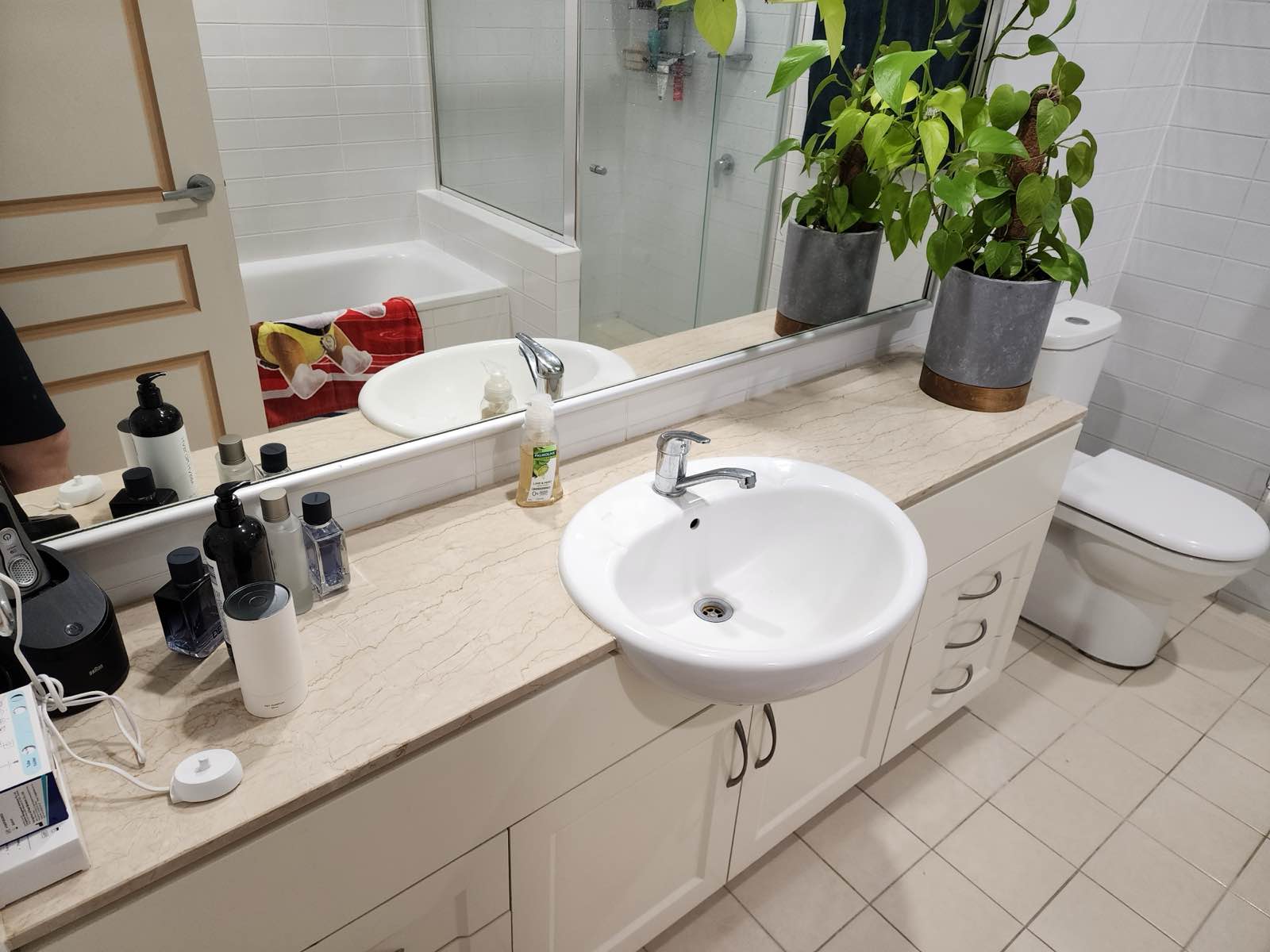 Ensuite before renovation: cream shaker-front vanity with an oval drop-in basin and chrome mixer