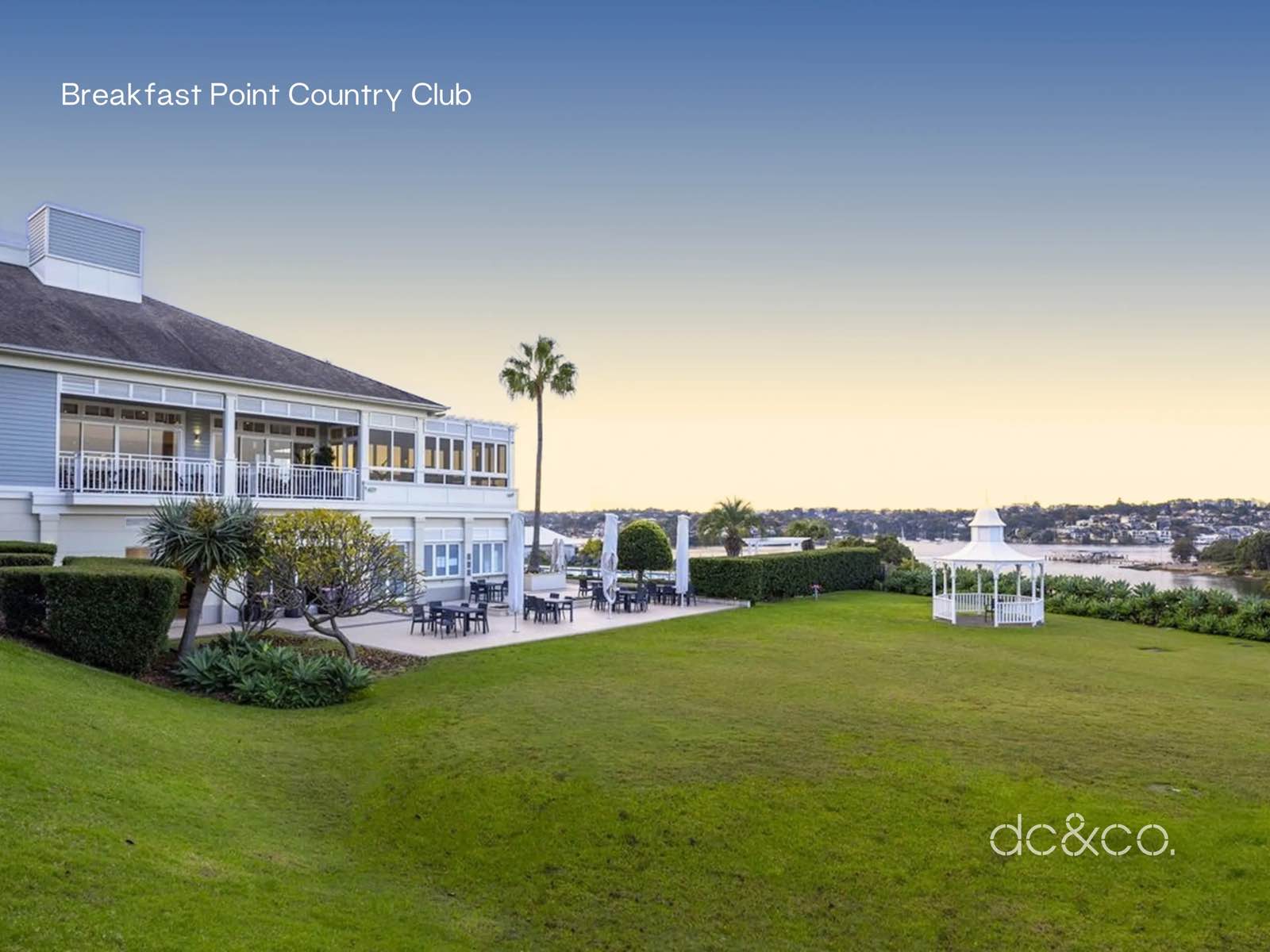 The Breakfast Point Country Club clubhouse above a lawn running down to the Parramatta River at dusk