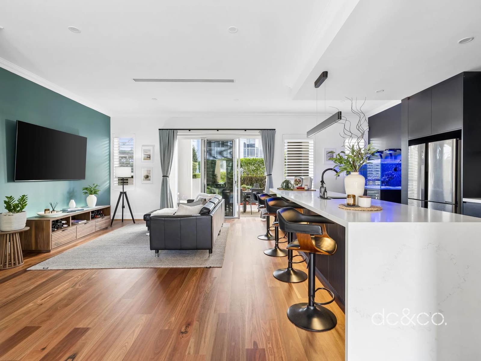 Living room looking through to the kitchen island and bar stools, timber floors throughout