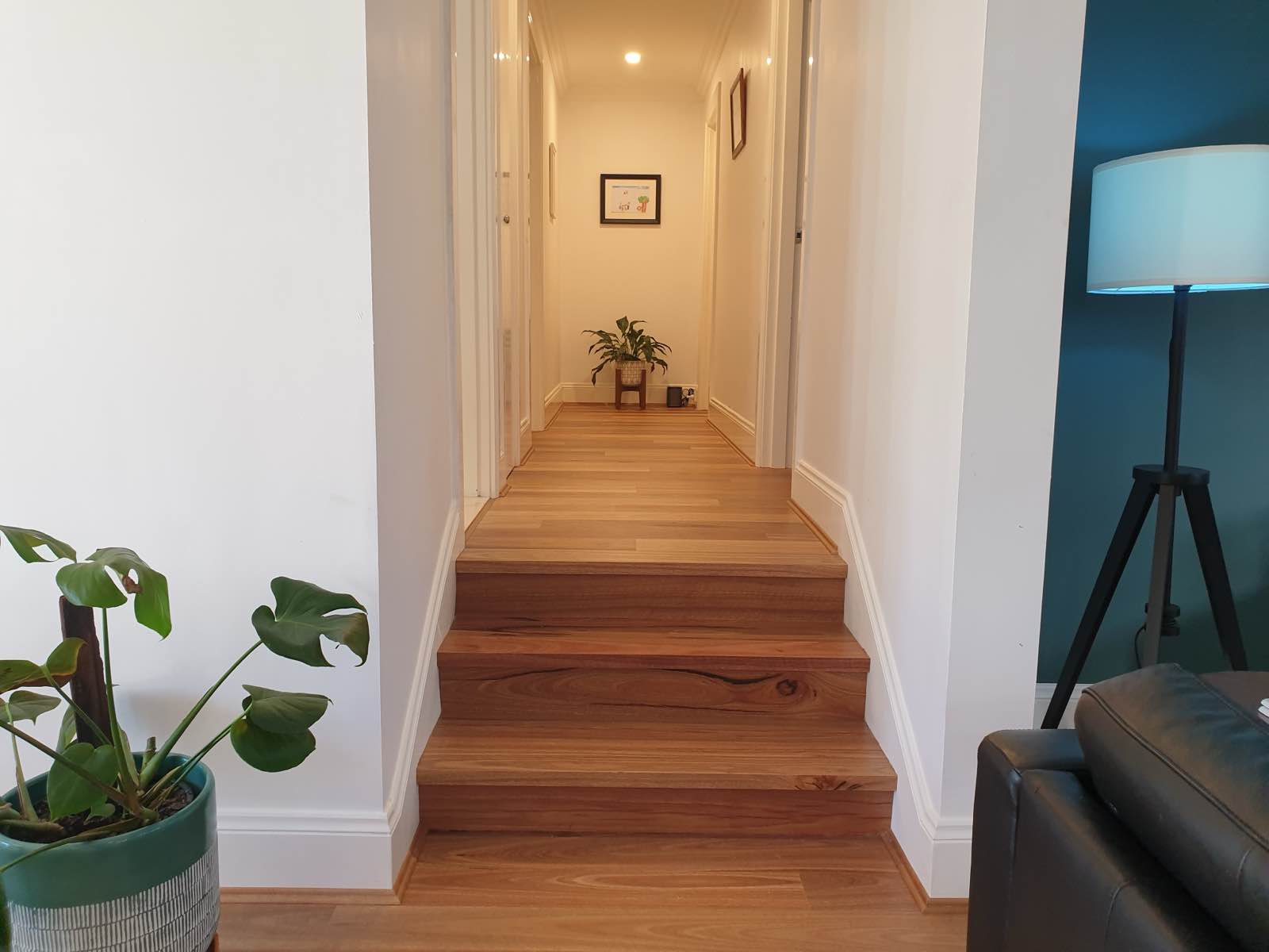 Three blackbutt timber steps leading from the living area up into the bedroom hallway